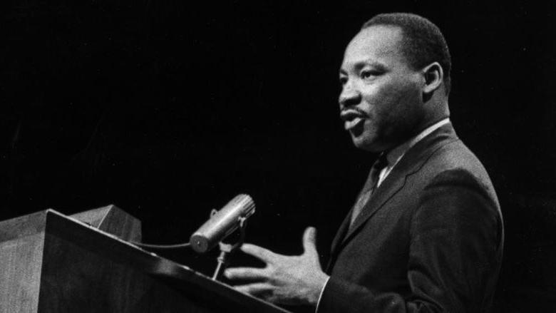 A black 和 white image of Martin Luther King speaking at a podium